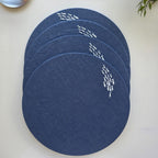 Four round navy blue placemats with white fish patterns, stacked on a light beige surface.