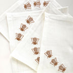 off white linen cocktail napkins with embroidered brown bees, arranged in a fan-like pattern on a white background. MI RE LA