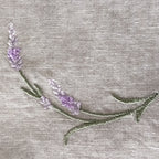 Close-up of a lavender floral embroidery on a light beige linen fabric  MI RE LA background.