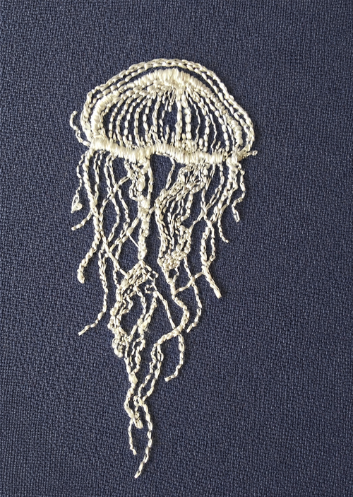 Embroidered jellyfish design on a dark fabric background