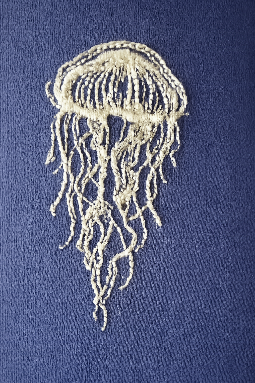 Embroidered jellyfish design on a blue fabric background