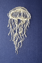 Embroidered jellyfish design on a blue fabric background