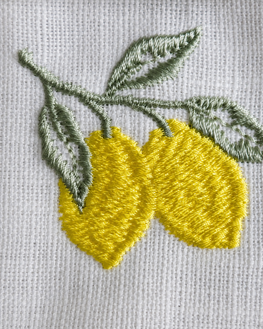 Embroidered design of lemons and leaves on a fabric background