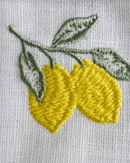 Embroidered design of lemons and leaves on a fabric background
