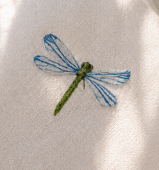 Embroidered dragonfly on a white fabric background