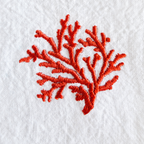A close-up of a coral branch embroidery design stitched in vibrant red-orange thread on a textured white fabric background. MI RE LA