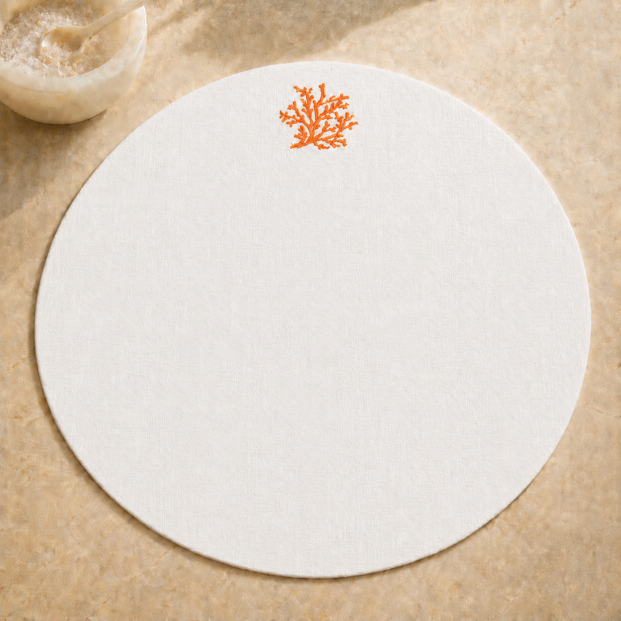 Off-white resin-coated linen round placemat with orange coral embroidery by MI RE LA