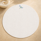 Off-white resin-coated linen round placemat with dragonfly blue embroidery by MI RE LA