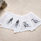 Four white square napkins with black line-art illustrations of skiers, a ski lift passenger, and another skier, arranged in a fan shape on MI RE LA a textured beige surface.